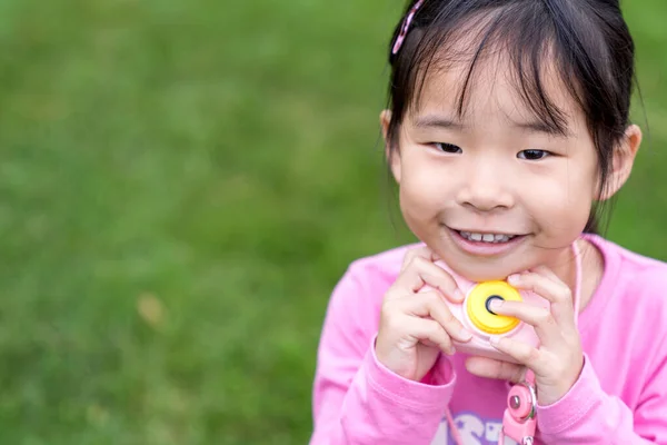 Aziatisch klein meisje met een plastic camera speelgoed — Stockfoto
