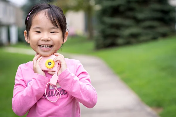 Asiática niña sosteniendo un plástico cámara juguete —  Fotos de Stock