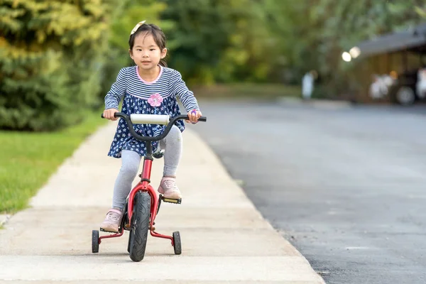 Bonito menina aprendendo a andar de bicicleta sem capacete — Fotografia de Stock