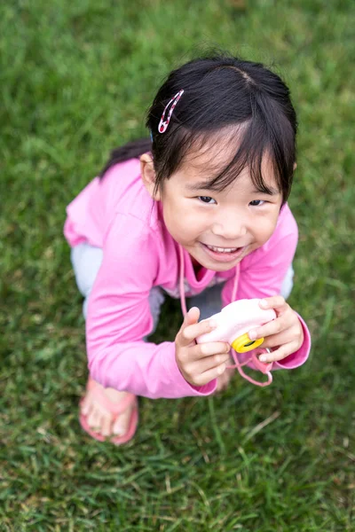 Asiática menina segurando um brinquedo de câmera de plástico — Fotografia de Stock