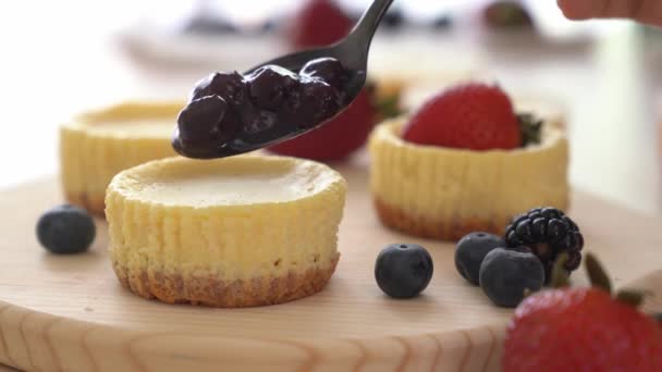 Ponga mermelada de arándanos encima de la mini tarta de queso Metraje De Stock Sin Royalties Gratis