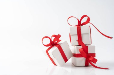 Noel, yeni yıl, sevgililer günü ya da doğum günü temalı kırmızı saten kurdeleli üç kare beyaz hediye kutusu. Kurdele, kutunun etrafında yansıtıcı beyaz bir yüzey etrafında dönüyor.