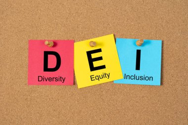 Bir mantar panoda her birinde bir harf ve DEI kısaltmasının karşılığı olan üç renkli yapışkan not yer alıyor: Çeşitlilik, Eşitlik ve Kapsama.
