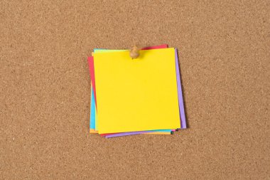 Tahtaya iğneyle tutturulmuş sade sarı yapışkan bir not. Boş not mesajlar, hatırlatıcılar veya yaratıcı fikirler için yer sağlar, ofis, okul veya ev kullanımı için çok yönlü hale getirir.