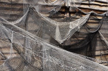 Ahşap duvarda asılı eski balıkçı ağları.         