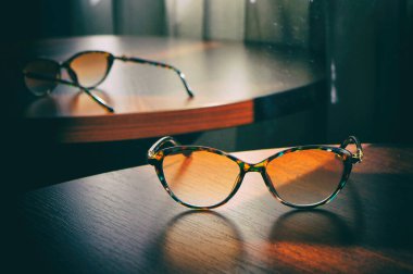 Yuvarlak masanın üzerinde bir çift gözlük ve içlerindeki aynada yansımaları. Seçici odak.                      