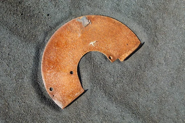 Rusty metal junk on black sand — Stock Photo, Image