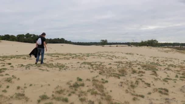Чоловік ходить в пошуках самотності в піщаних дюнах — стокове відео