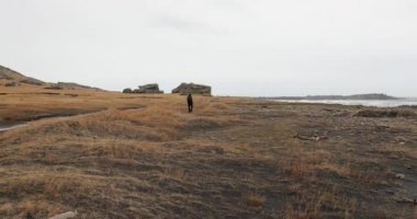 İzlanda 'da yürüyüş, sisli kayalıkların altında kara kumlarda yürümek.
