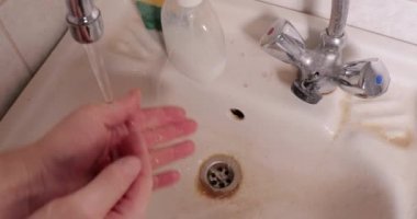 Kirli banyo lavabosunda ellerini yıkıyorsun.