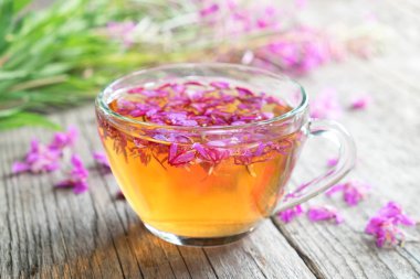 Fireweed sağlıklı bitki çayı. Chamerion çay ve odak değil, arka plan üzerinde şifalı otlar demet bir fincan.