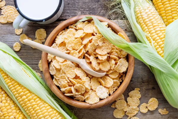 谷物玉米片 在木碗 牛奶杯和玉米芯在桌子上 顶部视图 — 图库照片