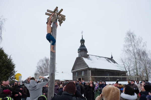 Азьярко, Минская область, Беларусь - 17 февраля 2018 года: Мальчик взбирается на деревянный столб на приз. Славянский народный праздник Масленица - символическая встреча весны. Минская область, пос. Азжарко, Беларус
.