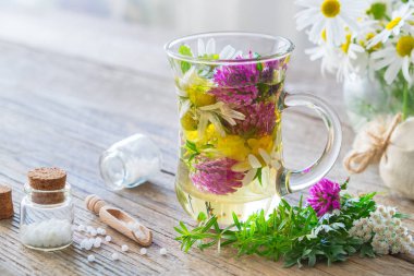 İki cam kupaları sağlıklı bitki çayı veya infüzyon, şişe Homeopatik globüller ve şifalı otlar. Homeopati ve bitkisel tıp.