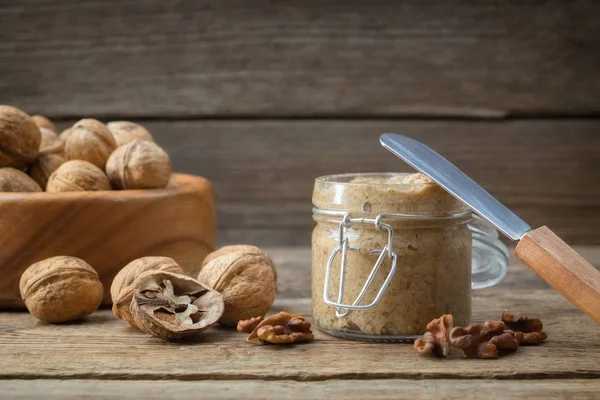 Pot rauwe biologische walnoot boter en verse noten op tafel. Ruimte voor tekst kopiëren. — Stockfoto