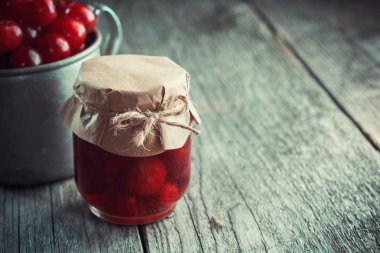 Kiraz reçel kavanoz ve olgun kiraz ahşap masa odaklanmak değil, bir fincan. Metin için yer kopyalayın.