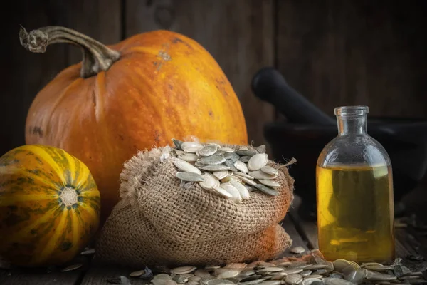 Pompoenpitten Olie Fles Twee Pompoenen Zak Van Zaden Mortel Achtergrond — Stockfoto