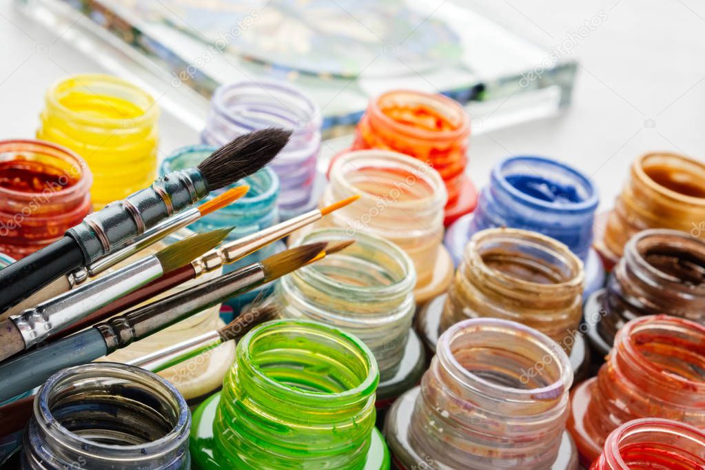 Stained glass paints and paint brushes, artisan painting  on a glass surface.