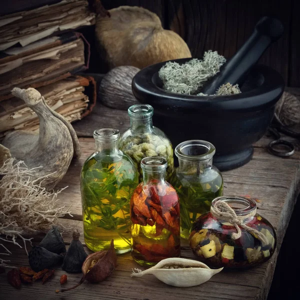 Flesjes etherische olie of potion, mortel van gedroogd mos, oude boeken, droge wortels en planten. Kruidengeneeskunde. — Stockfoto