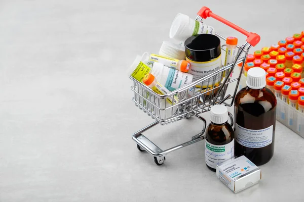 Mini shopping cart full of homeopathic remedies and first aid kit with different homeopathic preparation. Concept of buying homeopathic drugs. — Stock Photo, Image