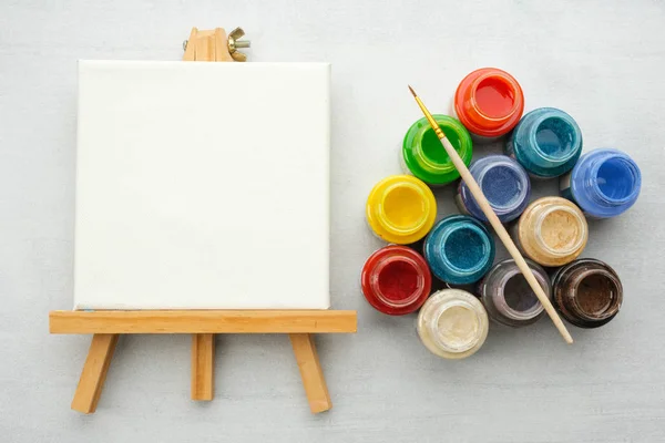Colorful paints with paint brush and canvas on the easels, top view. — Stock Photo, Image