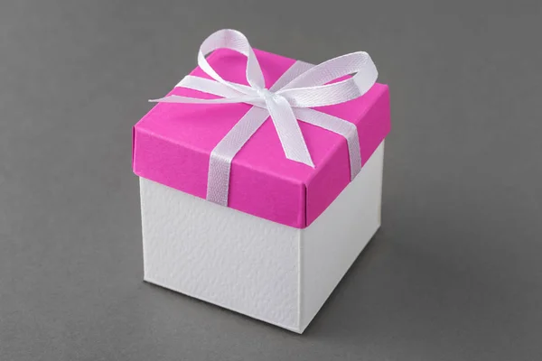 Geschenkbox mit rosa Bezug und Seidenschleife auf grauem Hintergrund. — Stockfoto