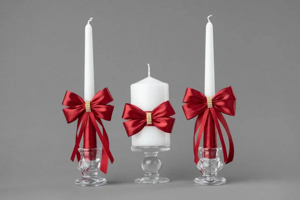 Wunderschöne Kerzen mit roten Seidenschleifen dekoriert. — Stockfoto
