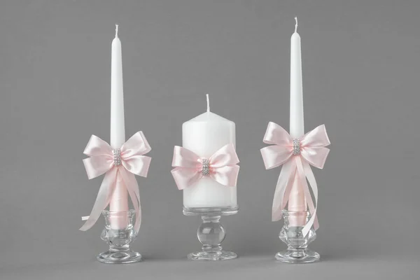 Wunderschöne Kerzen mit rosa Seidenschleifen dekoriert. — Stockfoto