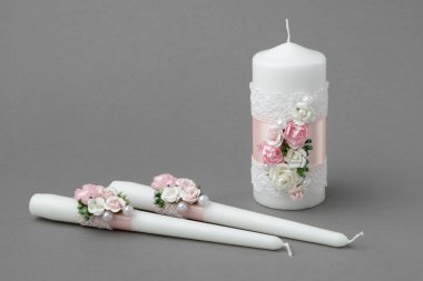 Güzel güller, inciler, pembe ipek kurdeleler ve dantellerle süslenmiş üç mum..