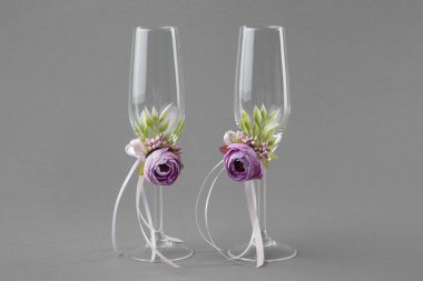 Mor çiçekler ve kurdeleler ile dekore edilmiş iki düğün şarap kadehi.