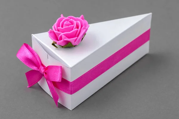 Papierschachtel als Kuchenstück. originelle kleine Geschenkschachtel mit rosa Schleife und Rose dekoriert. — Stockfoto