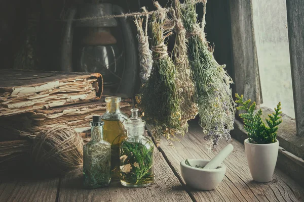 Botellas de infusión, libros antiguos, mortero y racimos colgantes de hierbas medicinales secas. Medicina herbal. Estilo retro . — Foto de Stock