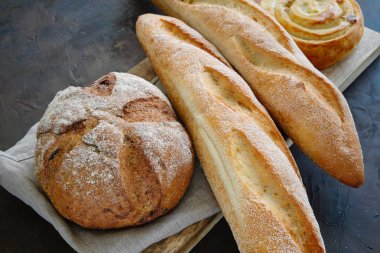 Keten peçete üzerinde taze pişmiş baget, ekmek ve çörek.