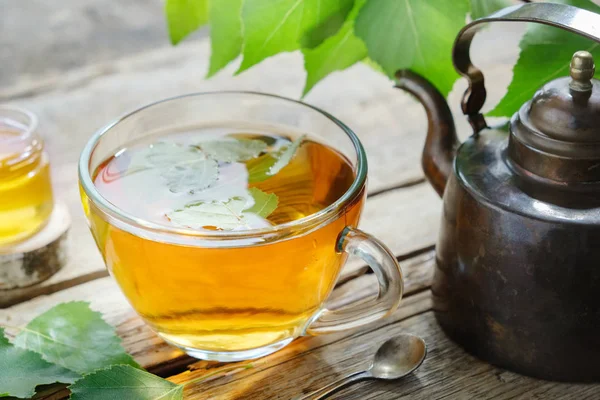 Liście brzozy, zdrowe ziołowe herbaty filiżanki, słoik miodu i rocznika miedzi herbaty czajnik. — Zdjęcie stockowe