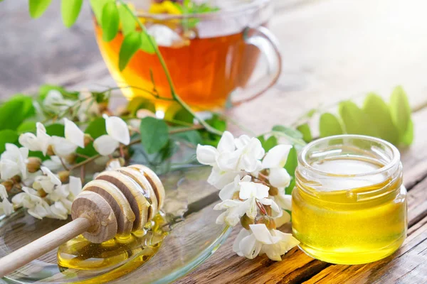 Acacia tree flowers honey jar, wooden dipper and healthy herbal tea cup. — Stock Photo, Image