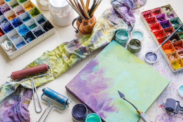 Artistic equipment in studio: canvas, palette knife, paint brushes, paints and palette. 