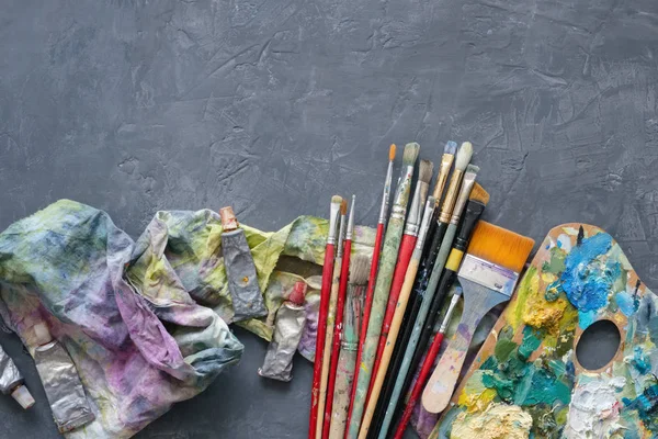 Konstnär målarpenslar, palett, palett knivar, målar rör på grå betong bakgrund. — Stockfoto
