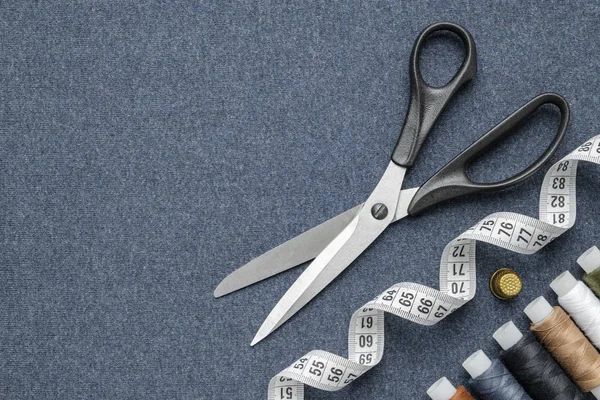 Naai artikelen: schaar, meetlint, vingerhoed, spoelen van veelkleurige draden. Naaien accessoires op naaien doek. Uitzicht vanaf boven. — Stockfoto