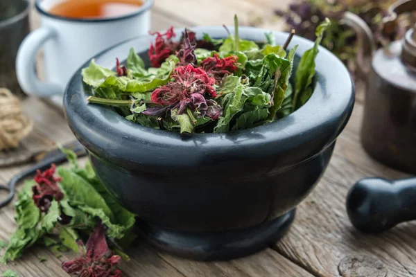 Mortaio nero di erbe medicinali, tazza smaltata di tisana e bollitore vintage su sfondo . — Foto Stock