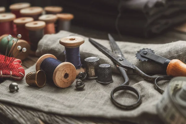 Vintage naaiwerk: retro kleermakersschaar, meetlint, meetlint, vingerhoed, houten draadspoelen, snijmes, kussen voor het opnemen van spelden, naalden en naaiaccessoires. — Stockfoto