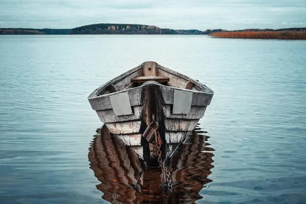 Wooden rowing boat with reflection in a still lake water at dusk — Stock Photo, Image