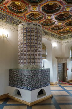 Mir Şatosu 'ndaki sergide dekore edilmiş eski moda yemek odasındaki döşemeli soba ve dekore edilmiş tavan. Mir, Grodno bölgesi, Belarus.