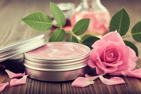 Jar with a homemade moisturizing beauty cream and pink rose flower.  Making of cosmetic products at home.