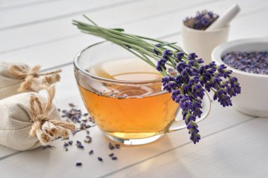 Bir fincan sağlıklı lavanta çayı ve lavanta çiçeği. Arka planda kuru lavanta ve kese var. Alternatif tıp.