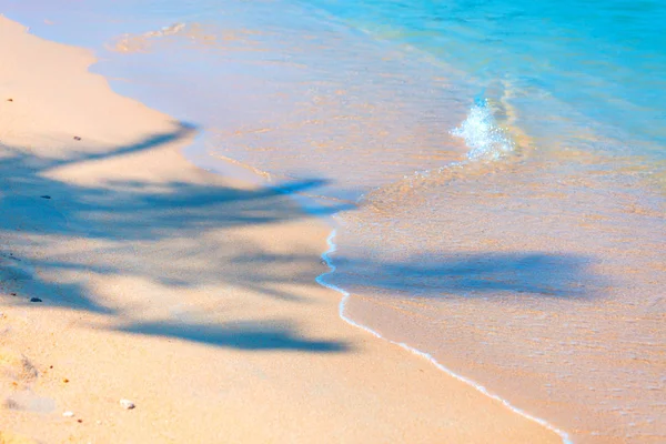 Sandstrand mit Palmenschatten und Schaumstoff auf einer kleinen Welle — Stockfoto