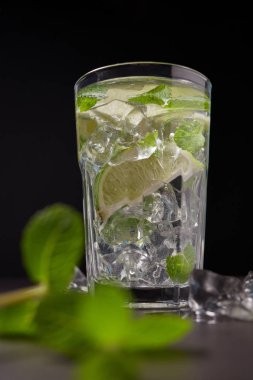 Buzlu Mojito kokteyl bardak ve malzemeler, kireç, buz ve nane yaprakları siyah arka plan üzerine, soğuk yaz içeceği 