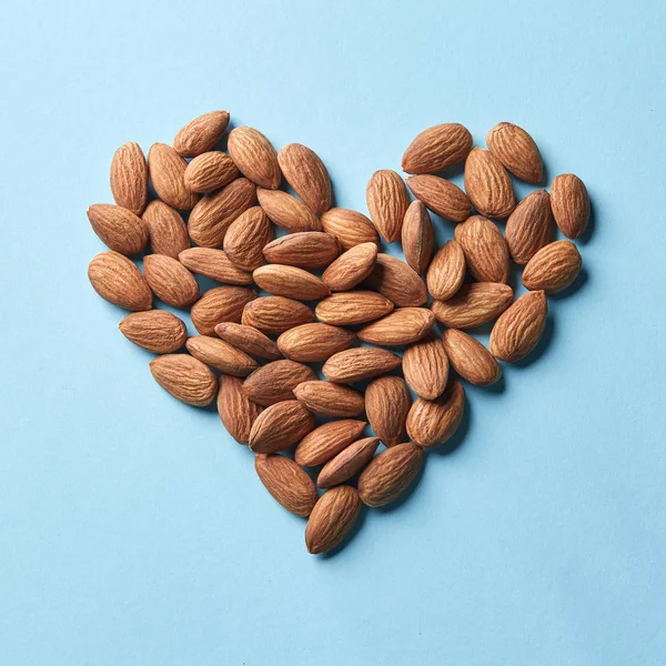 Pila Almendras Forma Corazón Sobre Fondo Azul Vista Superior Comida —  Fotos de Stock