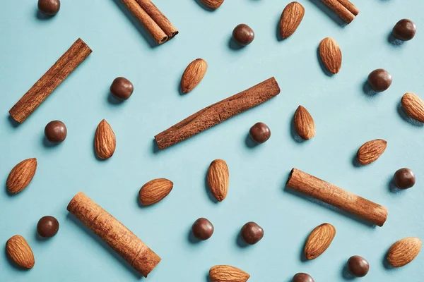 アーモンド シナモン スティックと青色の背景色 平面図 健康食品チョコレート ドロップ パターン — ストック写真