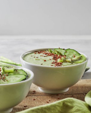 Yeşil yüzlü ile kase ıspanak, kivi, salatalık ve keten tohumu beton zemin üzerine yapılan