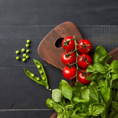 sağlıklı çiğ sebze gıda arka plan olarak ahşap masa, domates, bezelye ve fesleğen yaprakları üzerinde 